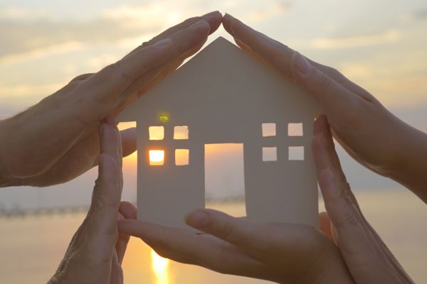 Florida Estate Planning concept: close up of two sets of hands holding a cutout of home